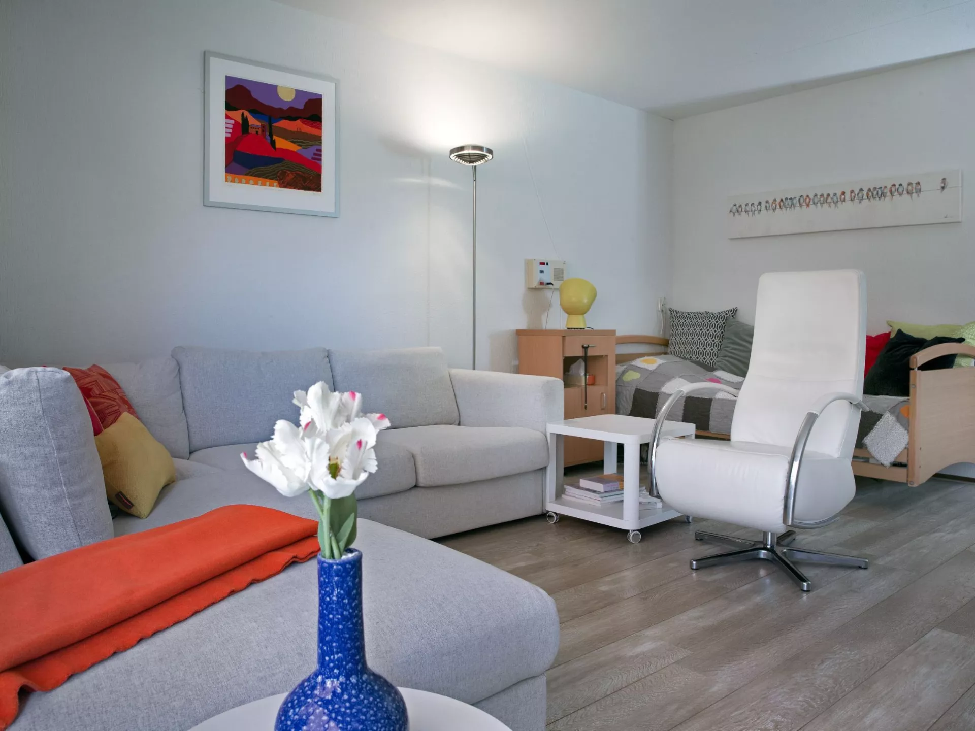 Moderne woonkamer met lichte meubels en een blauwe vaas met bloemen.