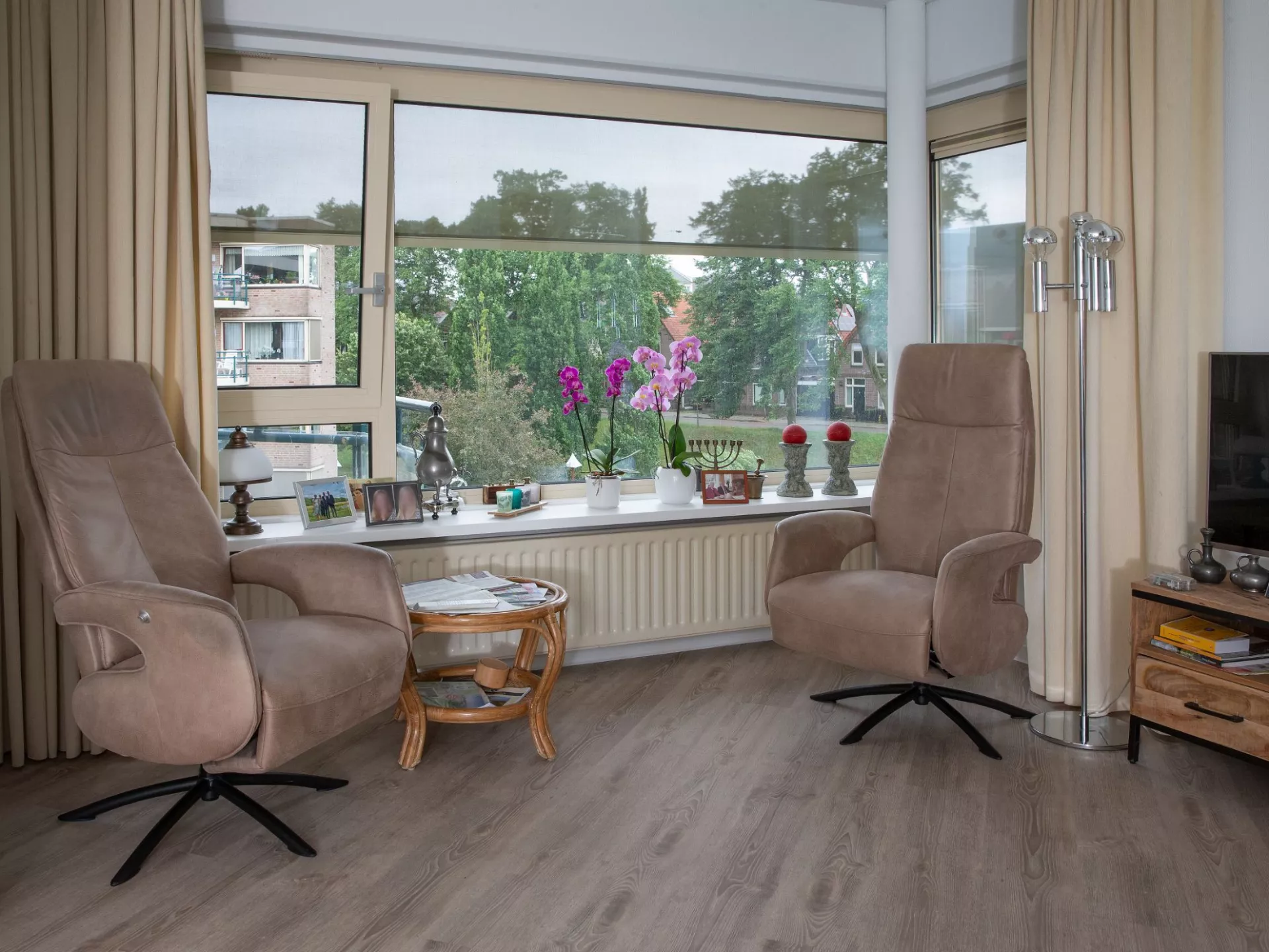 Knusse zithoek met twee fauteuils en een groot raam.