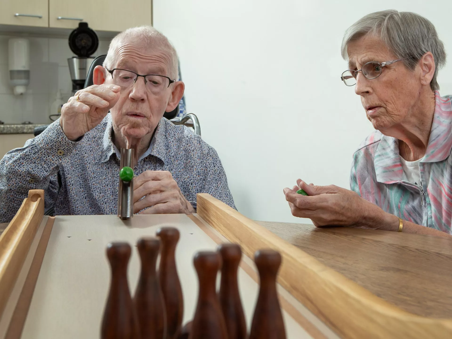 Een ouder stel speelt een potje tafelbowling thuis.