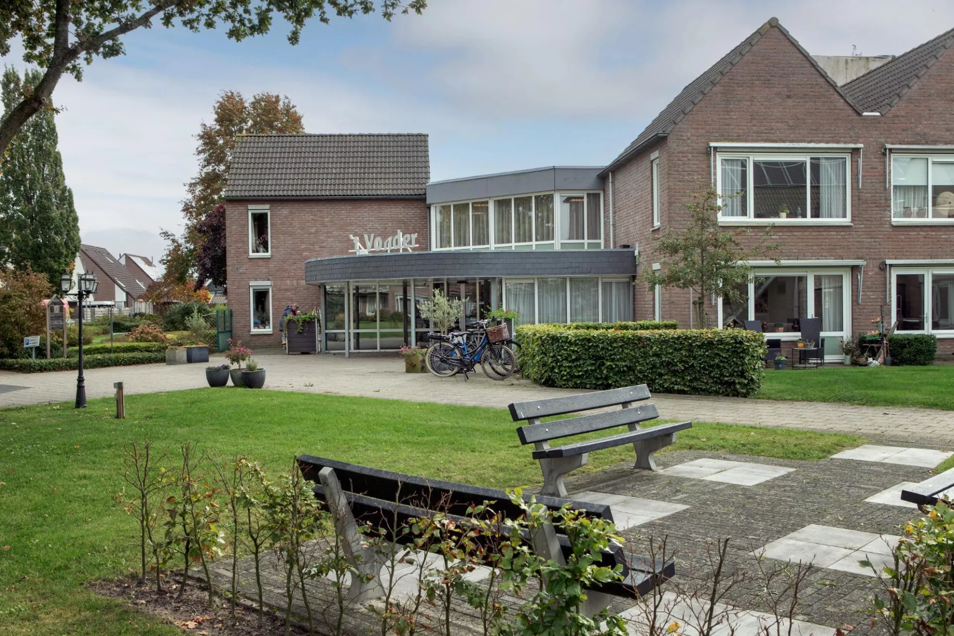 Vooraanzicht van 't Vonder omringd door een tuin en bankjes.